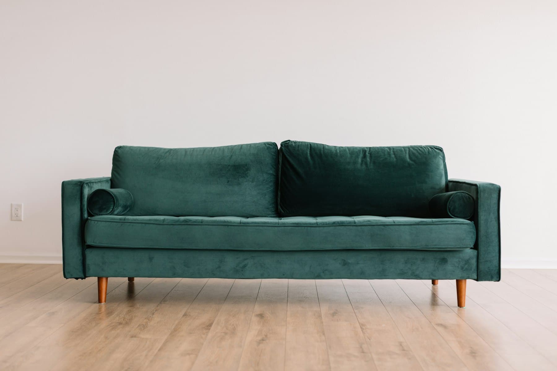 Green velvet sofa in an empty room awaiting furniture pickup